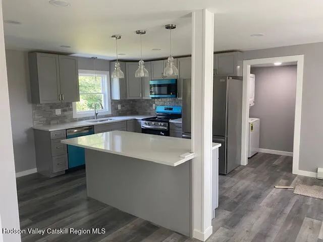 a kitchen with stainless steel appliances a sink a stove a refrigerator and cabinets