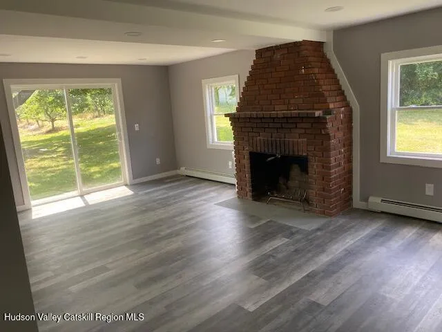 an empty room with wooden floor fireplace and windows