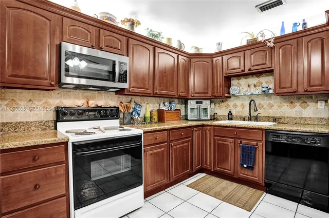 a kitchen with stainless steel appliances granite countertop wooden cabinets stove top oven and microwave
