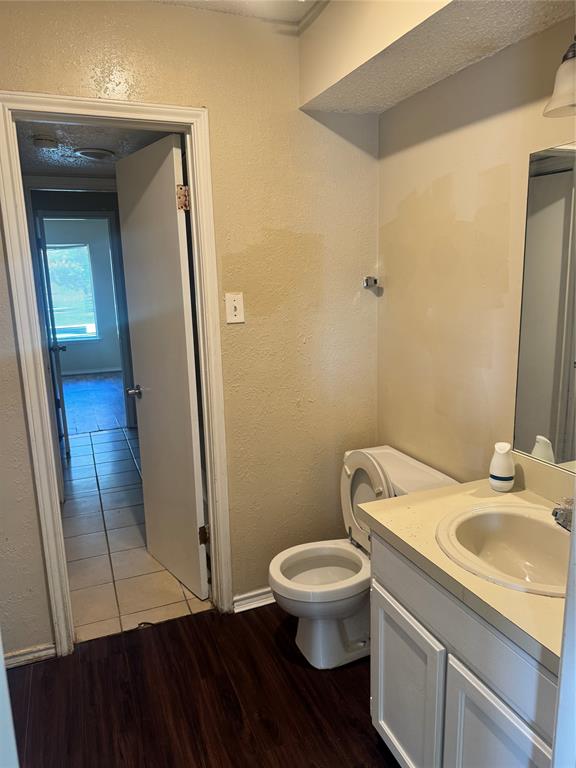 5617 Mansfield Road Arlington, TX 76017 - Photo 11 of 15 Bathroom featuring a vanity with a drop-in sink, white cabinetry, and a toilet