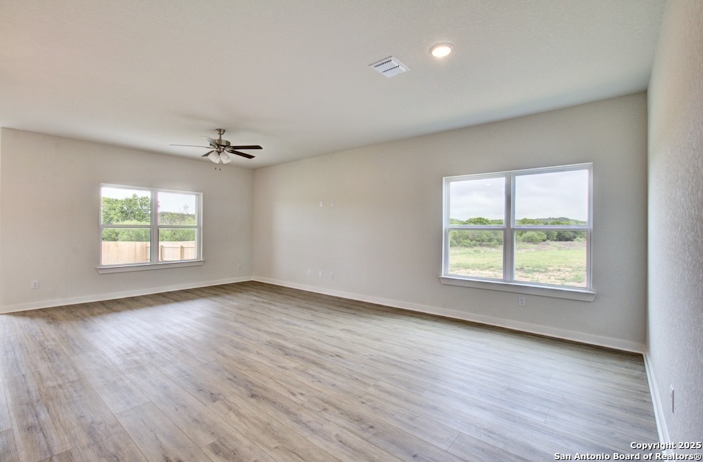 3625 Meteor Road New Braunfels, TX 78130 - Photo 22 of 39 an empty room with wooden floor chandelier fan and windows