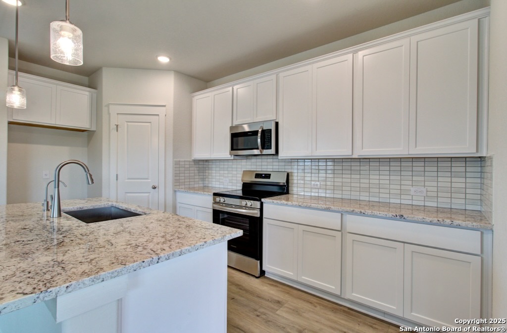 3625 Meteor Road New Braunfels, TX 78130 - Photo 3 of 39 a kitchen with granite countertop white cabinets and stainless steel appliances