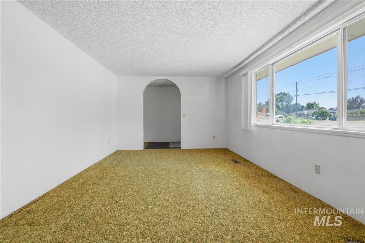 1311 North Middleton Road Nampa, ID 83651 - Photo 19 of 49 Spacious room featuring a large multi-pane window, arched doorway, light-colored walls, and textured ceiling