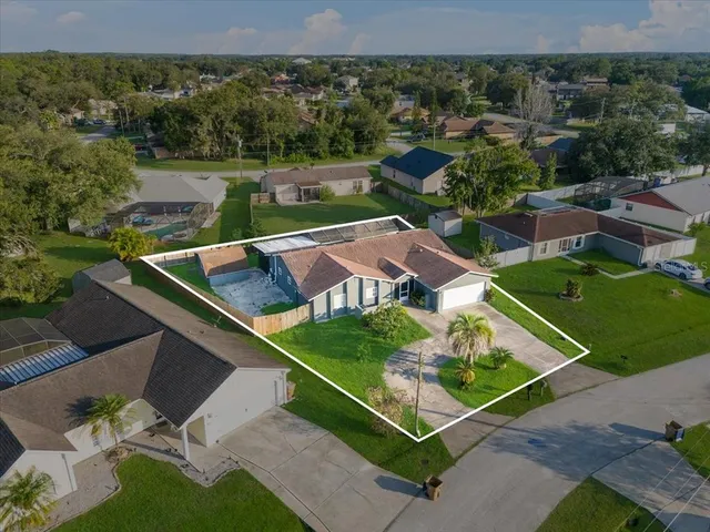 an aerial view of residential houses with outdoor space and trees