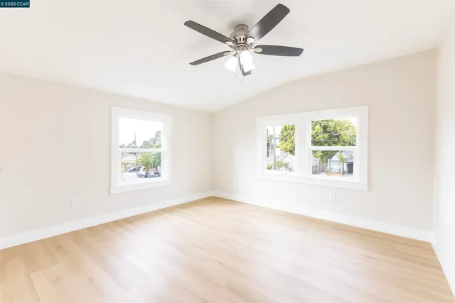 an empty room with windows and ceiling fan