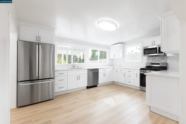 a kitchen with white cabinets stainless steel appliances and a window