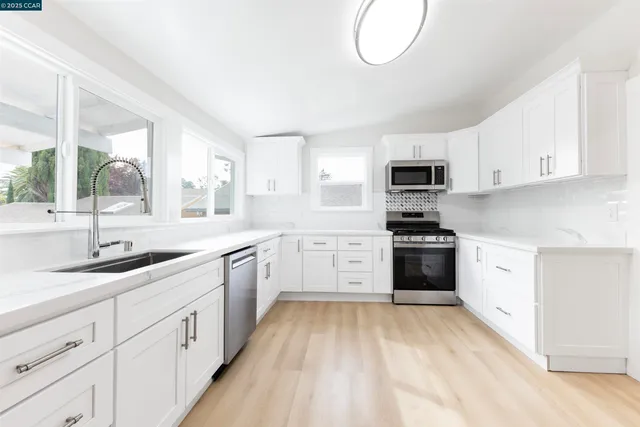 a kitchen with granite countertop white cabinets and stainless steel appliances