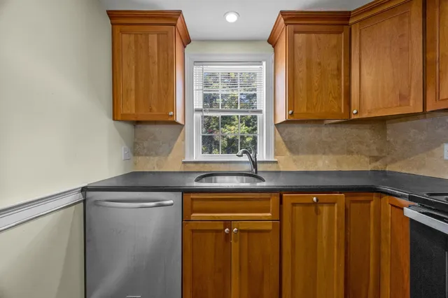 a kitchen with stainless steel appliances granite countertop white cabinets and a window
