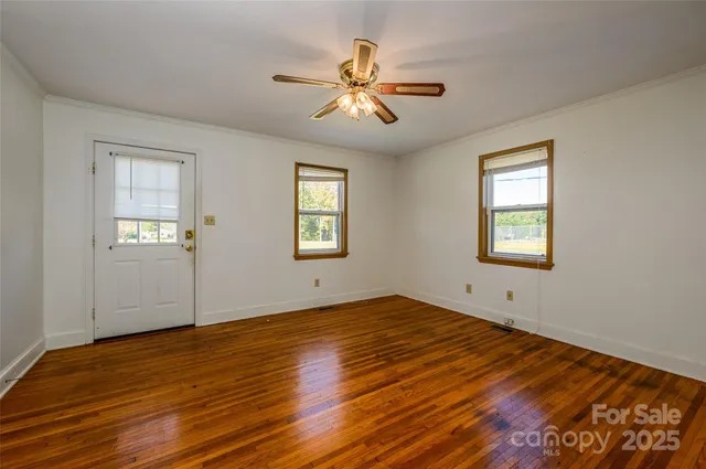 a view of an empty room with wooden floor and a window