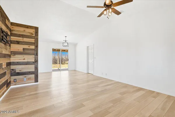 a view of empty room with wooden floor and fan