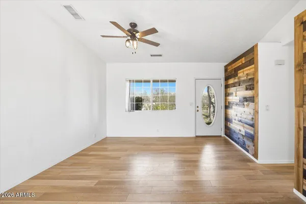 a view of an empty room with window and wooden floor