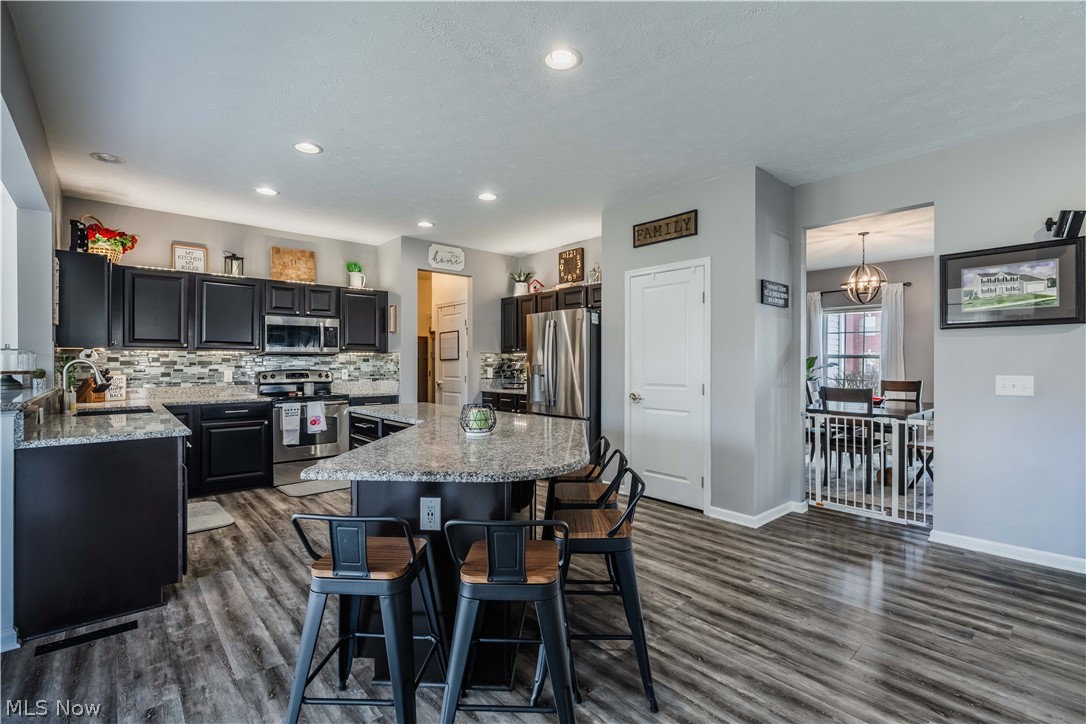 6687 List Street Northwest Canton, OH 44708 - Photo 8 of 21 Kitchen with a kitchen island, stainless steel appliances, a kitchen breakfast bar, and light stone countertops