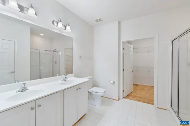 a bathroom with a double vanity sink toilet mirror and a shower