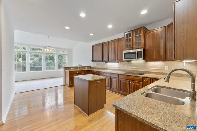 a kitchen with stainless steel appliances granite countertop wooden cabinets a stove top oven a sink and dishwasher with wooden floor