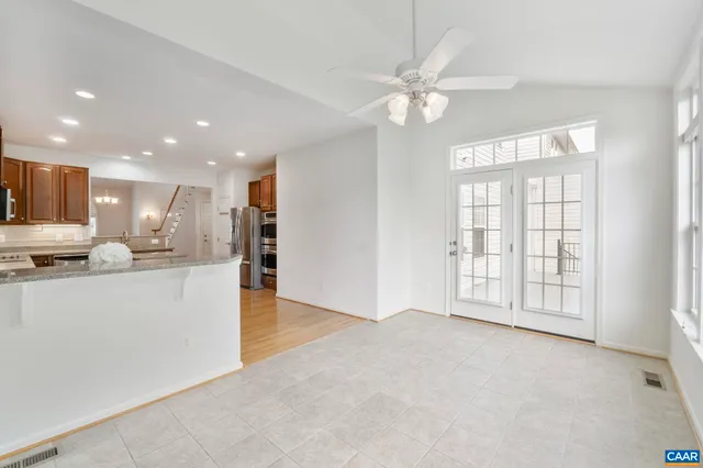 a view of an empty room with kitchen and window
