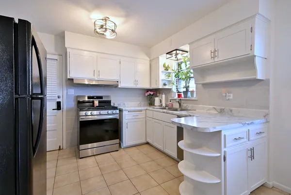 a kitchen with stainless steel appliances granite countertop a sink stove refrigerator and cabinets