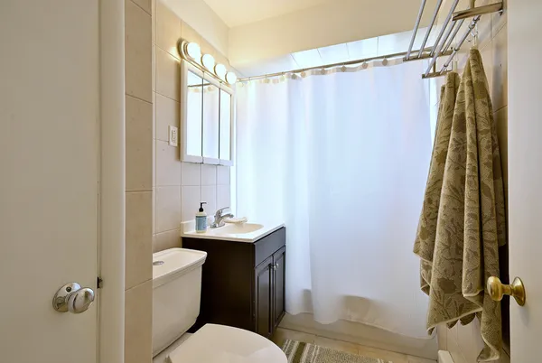 a bathroom with a sink a toilet a mirror and shower curtain