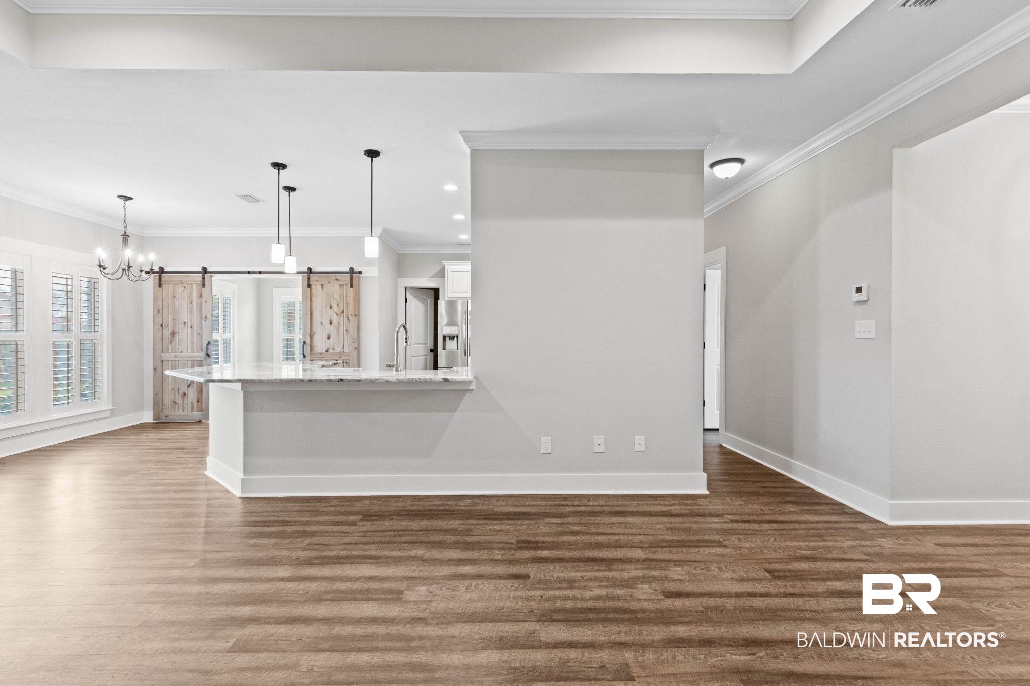 17376 Bankhead Boulevard Fairhope, AL 36532 - Photo 14 of 73 Unfurnished living room featuring a barn door, crown molding, a chandelier, dark wood finished floors, and recessed lighting