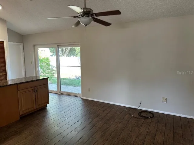 an empty room with wooden floor fan and windows