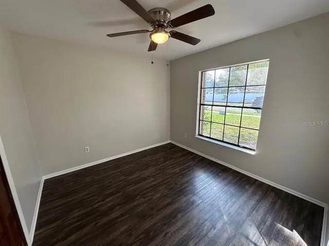 a view of an empty room with window and wooden floor