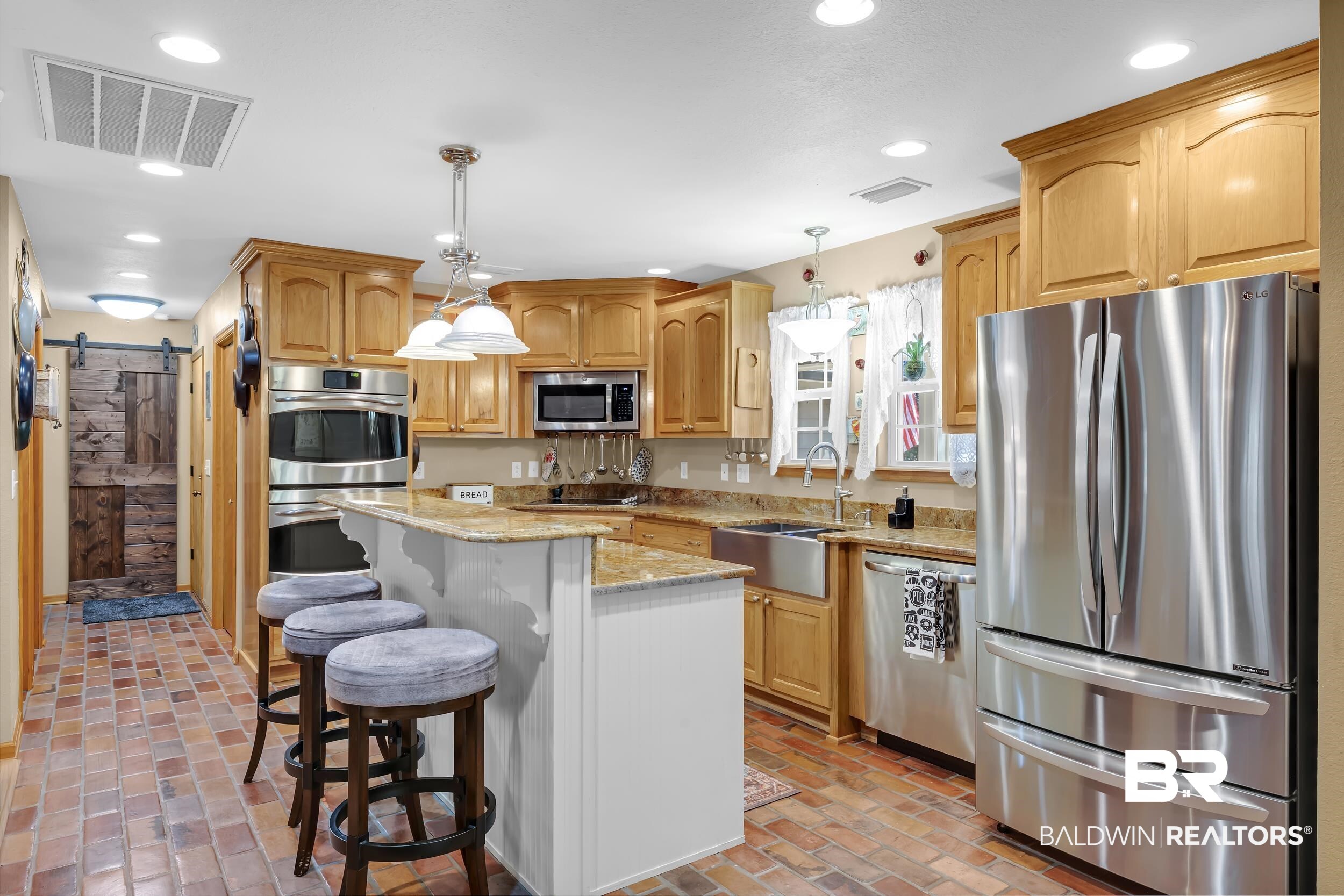 22929 Highway 98 Foley, AL 36535 - Photo 5 of 54 Kitchen featuring a barn door, stainless steel appliances, light stone counters, hanging light fixtures, and a breakfast bar area
