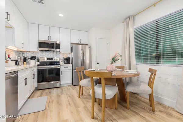 a kitchen with stainless steel appliances a dining table chairs microwave and refrigerator