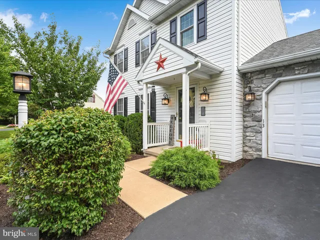 a view of a white house with a small yard and plants
