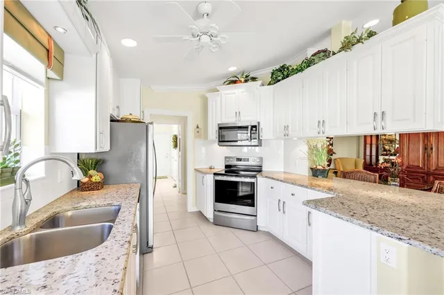 a large kitchen with granite countertop a sink a counter top space stainless steel appliances and cabinets