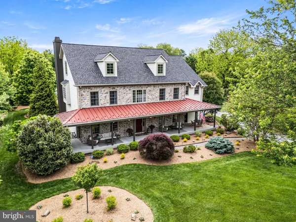 a view of a big house with a big yard and potted plants and large tree