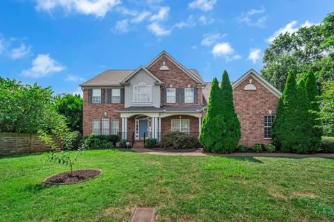a front view of a house with a yard and trees