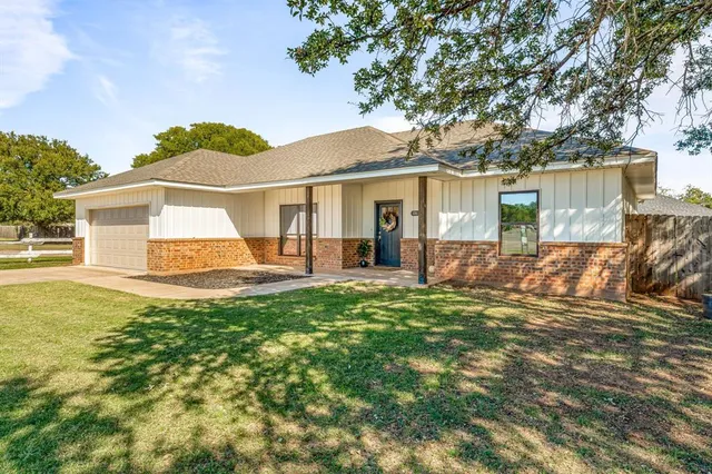 a view of a house with backyard and a tree