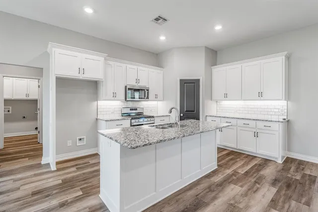 a kitchen with stainless steel appliances granite countertop a sink stove microwave and refrigerator