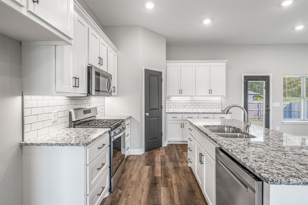 1501 Johnson Road, Unit A Iowa Park, TX 76367 - Photo 12 of 30 a kitchen with stainless steel appliances granite countertop a sink stove microwave and refrigerator