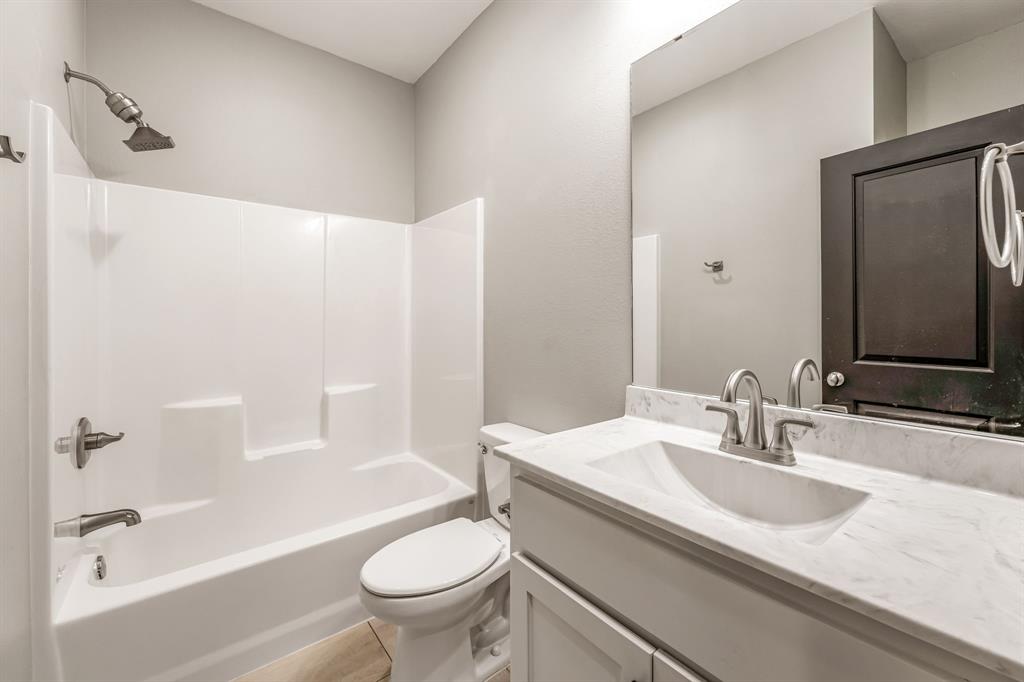 1501 Johnson Road, Unit A Iowa Park, TX 76367 - Photo 25 of 30 a bathroom with a granite countertop sink toilet and shower