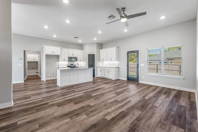 a view of kitchen with kitchen island wooden floors appliances and cabinets