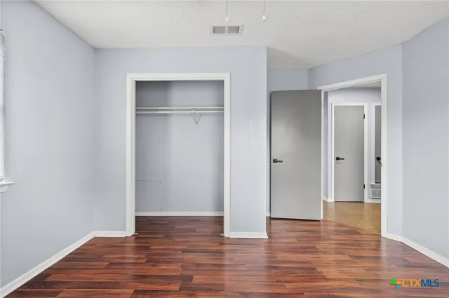 a view of empty room with wooden floor