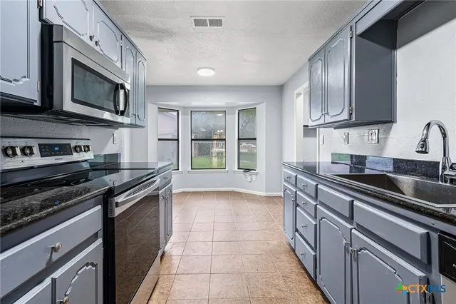 a kitchen with stainless steel appliances granite countertop a stove microwave and sink