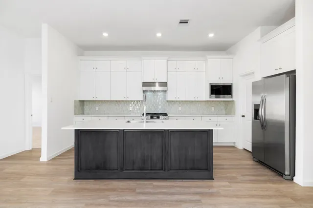a view of a kitchen with stainless steel appliances granite countertop a sink and cabinets