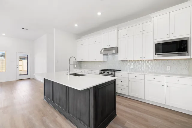 a kitchen with stainless steel appliances granite countertop a sink stove and cabinets