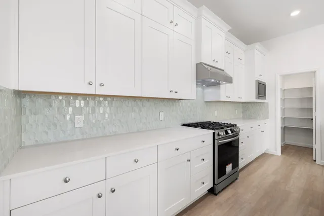 a kitchen with stainless steel appliances granite countertop white cabinets and a stove a oven with white countertops