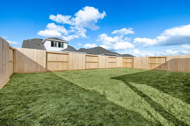 a view of a backyard with plants & a barbeque