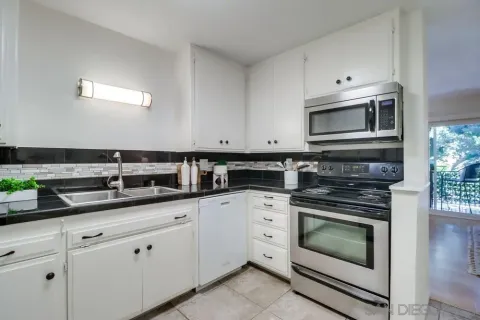 a kitchen with granite countertop white cabinets and stainless steel appliances