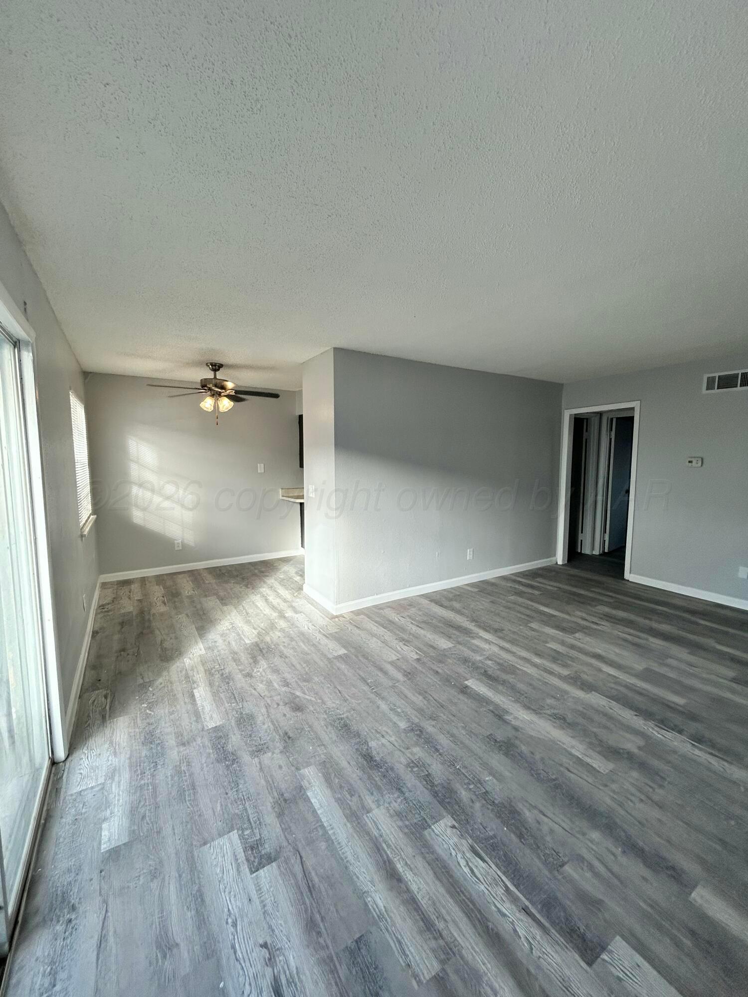 3020 Southwest 27th Avenue Amarillo, TX 79109 - Photo 9 of 18 an empty room with wooden floor and windows