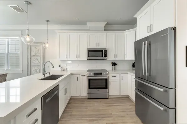 a kitchen with stainless steel appliances granite countertop a sink a stove a refrigerator and chairs with wooden floor