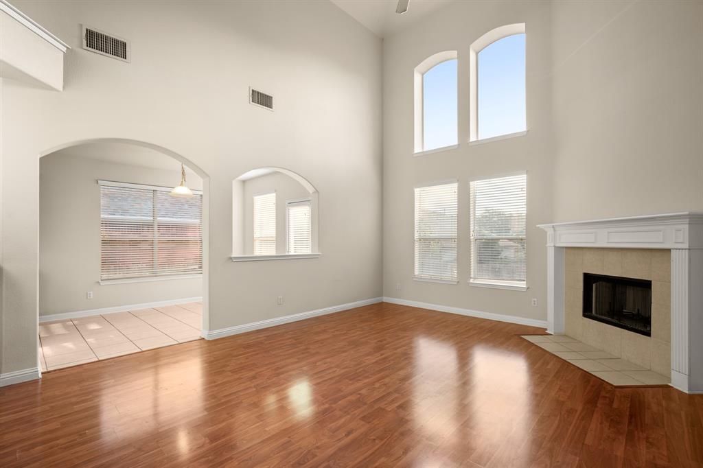 10105 Wind Cave Trail Austin, TX 78747 - Photo 3 of 23 Living area featuring high ceilings, wood-finish flooring, a fireplace with a mantel, and arched window openings