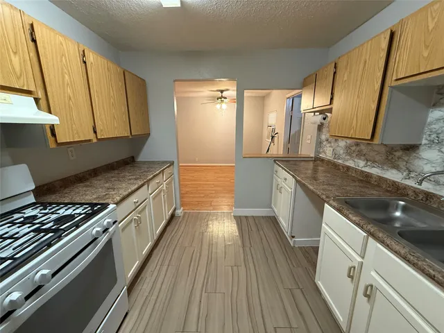 a kitchen with kitchen island granite countertop a sink stove and cabinets