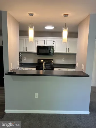 a view of kitchen with granite countertop a sink a stove and cabinets