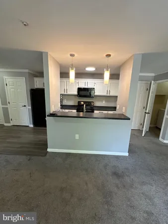 a view of a kitchen with kitchen island a sink wooden floor and a counter top space