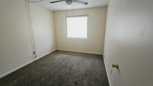 an empty room with a ceiling fan and a window