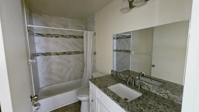 a bathroom with a granite countertop sink toilet and shower